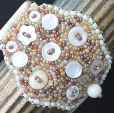 "This Apple watch band is lovingly hand embroidered with vintage beads  and a wide variety of embellishments and is backed securely with buttery  Ultra Suede. Silver-toned connectors attach this bracelet to your  38-40,41mm Apple watch. Because of the variety in bead hues, this watch band  coordinates well with all stainless steel, yellow gold, rose gold, silver, and  space gray cases.  This 2 1/4\" wide watch band is fully adjustable from wrist size 6\" and up  simply by creating an overhand knot (see diagram with video at bottom  of page) in expandable elastic to perfectly fit your wrist. Because you  customize the fit, the watch will hug snugly and comfortably." Handmade Vintage Cream Bracelets, Vintage Handmade Cream Bracelets, Vintage White Beaded Bracelet, Overhand Knot, Apple Watch 3, Apple Band, Bracelet Apple Watch, Rose Tone, Vintage Beads