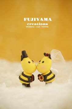 two small yellow and black bee figurines with veils on their heads, standing next to each other