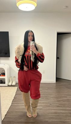 a woman is taking a selfie with her cell phone in the living room while wearing red and black clothing