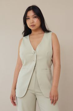 Our On Time Vest is an elongated sage green vest style top. It features a button front closure, seams along each side of the mid bodice, pocket details, and a v neckline. Pair it with our On Time Trousers for the cutest matching set look!Model wears a size smallModel is 5'1" (photos) Model is 5'5" (video)96% Polyester, 4% SpandexSize small measurements:Bust: 33"Waist: 42" Sage Green Vest, Autumn Soft, Vest Style, Soft Dramatic, Green Vest, Large Clothes, Cropped Vest, Soft Autumn, Cozy Gift