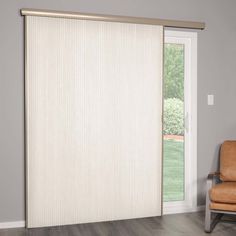 a living room with a chair and sliding glass door that has blinds on it's side