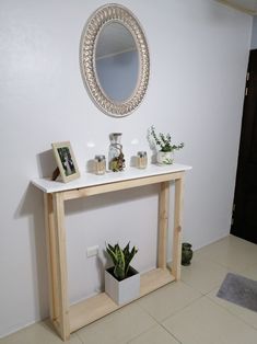 a white table topped with a mirror and potted plant next to a wooden shelf