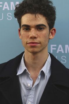 a young man with freckled hair wearing a black jacket and button up shirt