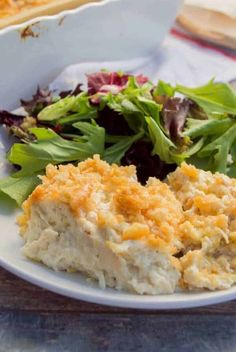 a close up of a plate of food with salad and bread in the background on a table