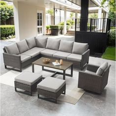 an outdoor living room with grey wicker furniture and white rugs on the floor