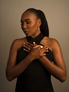 a woman in a black dress holding her hands together