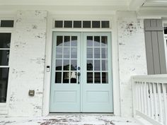 a white brick house with two blue doors