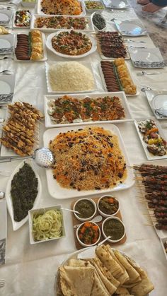 a table filled with lots of food on top of white tables cloths and plates