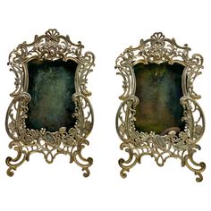 two ornate gold frames with green glass in the middle and one on each side, set against a white background