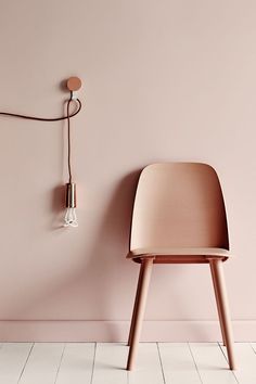 a chair and lamp against a pink wall