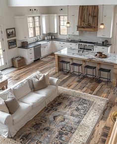 a large living room and kitchen area with hardwood floors, white cabinets, and an old rug on the floor