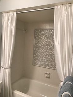 a bath tub sitting under a window next to a curtain