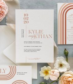 the wedding stationery is laid out on top of each other, with flowers and greenery