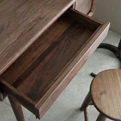 a wooden desk with two stools next to it and an open drawer in the middle