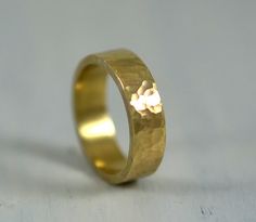 a gold wedding ring on a white surface with the light reflecting off it's side