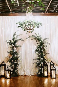 the wedding arch is decorated with greenery and lanterns