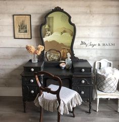 an antique desk with a mirror, chair and other furniture in front of the wall