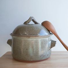 a large pot with a wooden spoon in it on a wood table next to a white wall