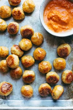 some kind of appetizer that is sitting on a baking sheet with sauce in the background