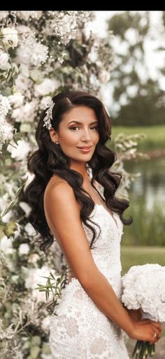 a woman in a wedding dress standing under a flower covered arch with flowers on it