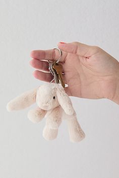 a hand holding a keychain with a stuffed animal hanging from it's side