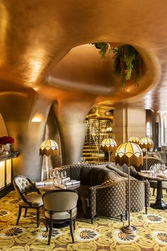 the interior of a fancy restaurant with round tables and chairs, gold ceilinging and chandeliers