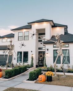 halloween decorations in front of a house with skeletons on the lawn and pumpkins outside