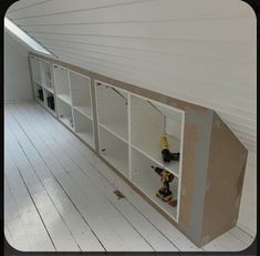 an unfinished bookcase with tools on it in the middle of a room that is being painted white