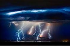 lightning strikes in the night sky over a body of water with dark clouds and bright lights