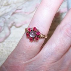 Dating To The Late 1880s/1890s Or So, May I Offer This 14k Rose Gold (Tested, Not Marked) Engagement Ring - Sweetheart Ring - Fashion Ring Featuring A Top Design Of 2mm Faceted Round Pink/Red Quartz (Tested) Acting As A Halo Around A 4.5mm Moonstone Cab. The "Florette" Design On The Top Measures 3/8" High/Wide; Ring Size Is A 5 On My Sizer. Weight Is 2 Grams. There's A Lovely Bit Of Repousse Work To Either Side Of The Center Design. The Inside Shank Of The Ring Is Unmarked For Gold Which Was Not A Requirement To Do Until The Federal Stamping Act Of 1906 However, The Inside Of The Ring Is Designer Signed - Hm Conjoined Within A Stylized Buttercup Round. Very Fine Condition With No Problems I Quartz Engagement Ring, Red Quartz, Wide Ring, Engagement Ring Sizes, Pink Quartz, Antique Victorian, Womens Jewelry Rings, Fashion Rings, Wedding Rings Engagement