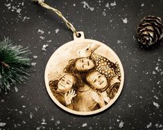 a christmas ornament with an image of three women on it and pine cones