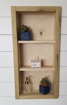 three wooden shelves with plants and soap dispensers on them against a white wall