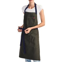 a woman wearing an apron and smiling at the camera with her hands in her pockets