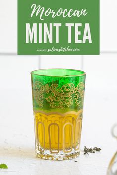 a green and yellow glass with the words moroccan mint tea on it next to some leaves