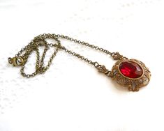 Beautiful victorian style pendant necklace made of a lovely oxidized brass filigree cabochon base, American made, and a vintage ruby red rhinestone cabochon. The size of the cabochon is 13 x 18 mm. The necklength is approximately 49 cm. (19.3 inches) For more jewelry please visit our shop: http://www.minouc.etsy.com For combined shipping please contact us. We also combine shipping with our other Etsy shop where we sell vintage fabrics and finds from Holland and France: http://www.minoucbrocante. Victorian Brass Necklace For Valentine's Day, Victorian Antique Gold Necklaces For Valentine's Day, Antique Red Necklace For Wedding, Victorian Antique Gold Necklace For Valentine's Day, Victorian Red Jewelry With Vintage Charm, Victorian Ruby Pendant Jewelry, Victorian Style Brass Necklace With Oval Pendant, Antique Red Pendant Jewelry, Red Oval Victorian Necklace