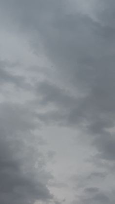 an airplane is flying high in the sky on a cloudy day with dark clouds behind it