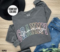 You will love our Comfort Colors Grammy long sleeve t shirt. It says, Grammy in an alternating colorful font with a script font overlay that says Grammy. This long sleeve Grammy tee would make a great Grammy Birthday gift, Grammy Christmas gift or Grammy Mother's Day gift. It comes in 3 beautiful Comfort Colors brand t shirt colors, pepper, light green and blue jean. Link to short sleeve t-shirt: https://etsy.me/3TPf3OW Link to Sweatshirt: https://etsy.me/3XGyUAN Link to Long Sleeve Shirt: https Grammy Tshirt Ideas, Grammy Shirt Ideas, Trendy Long Sleeve T-shirt With Lettering, Multicolor Long Sleeve T-shirt With Text Print, Black Long Sleeve T-shirt With Custom Text, T Shirt Colors, Grammy Gift, Cricut Maker, Script Font