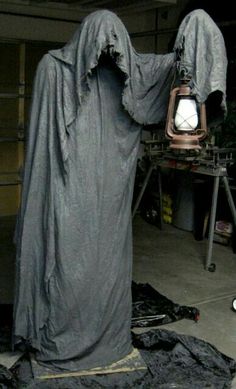 a creepy looking statue with a lantern in it's hand and some sort of cloth on the ground