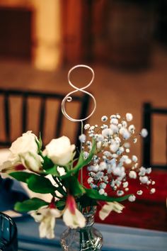 the table is set with an elegant centerpiece and white flowers in a clear vase