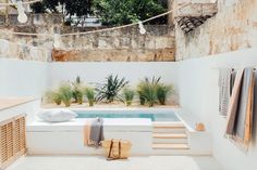 an outdoor hot tub with towels hanging from the ceiling and plants in pots next to it