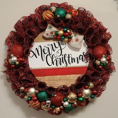 a christmas wreath hanging on the wall with ornaments around it and a sign that says merry christmas