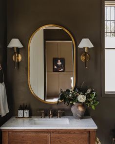 a bathroom vanity with a large mirror and flowers on the counter top in front of it