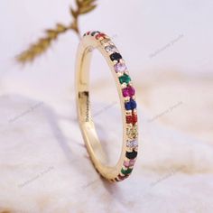 a yellow gold ring with multicolored stones on the side and a single flower in the middle