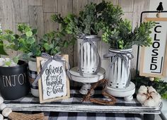 three white vases with plants in them on a black and white checkered table cloth