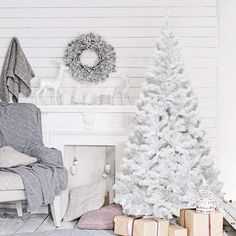 a white christmas tree sitting in front of a fireplace