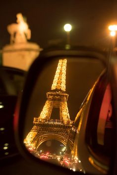 the eiffel tower is seen in the rear view mirror of a car at night