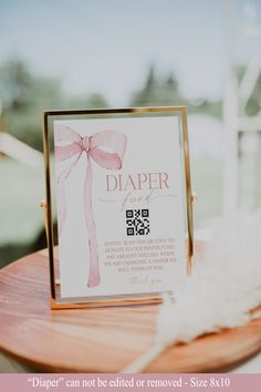 a diaper sign sitting on top of a wooden table next to a white feather