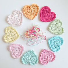 crocheted hearts arranged in a circle on a white surface with the word love written across them