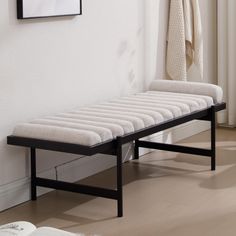 a white bench sitting next to a wall with a towel hanging on it's side