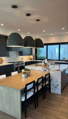 a large kitchen with an island in the middle and two pendant lights hanging from the ceiling